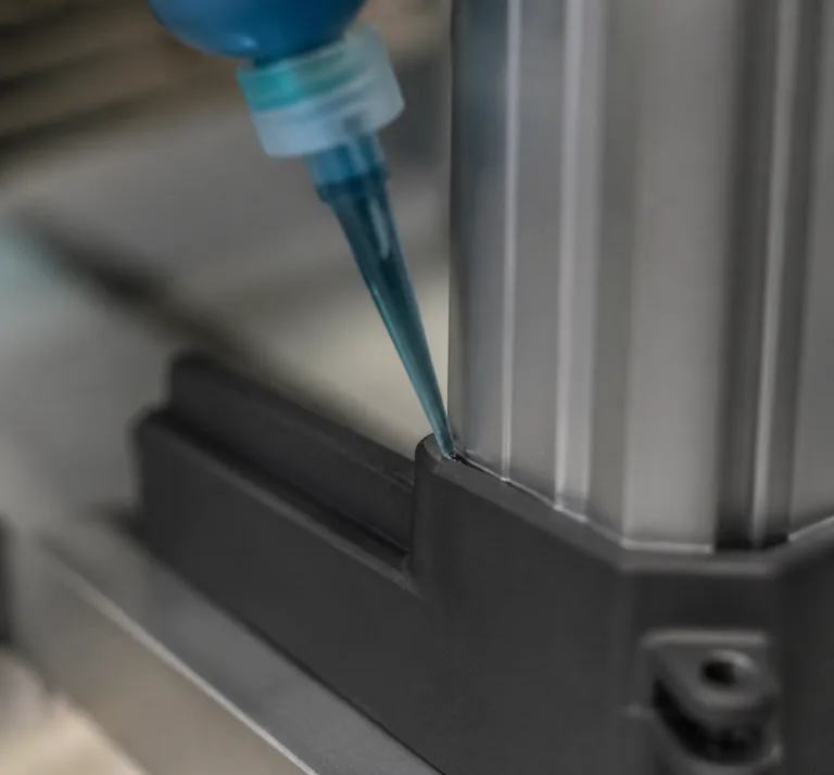Applications 2 A detailed industrial product photo showing precision adhesive bonding between metal and plastic or metal components in a clean manufacturing environment.