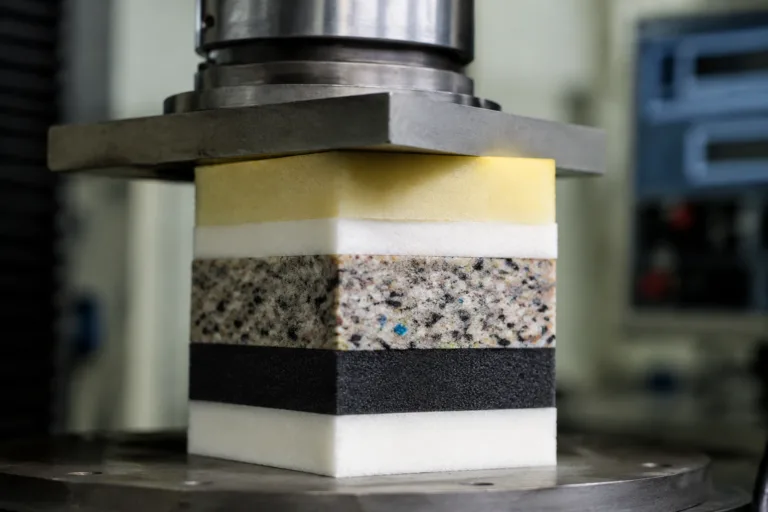 Foam Adhesive 17 A clean, realistic close-up of bonded foam composite materials in a durability testing environment, emphasizing soft-material stability under compression, humidity, heat, repeated handling, and vibration.