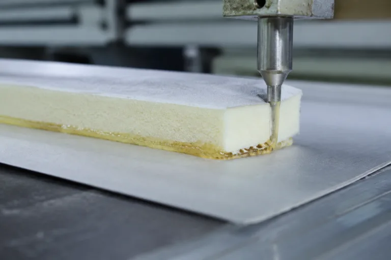 Laminating Adhesive 5 A realistic close-up of foam laminating adhesive application during material manufacturing, featuring a visible layered structure as foam is bonded to fabric or film for cushioning or insulation products.