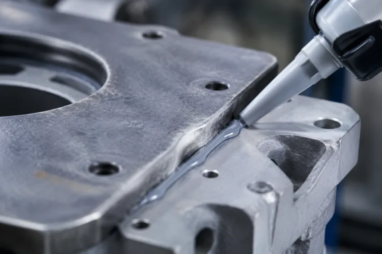Sealing Adhesive 7 A professional close-up manufacturing scene showing sealant being applied to fill an uneven assembly gap between two industrial components, emphasizing its protective and sealing function.