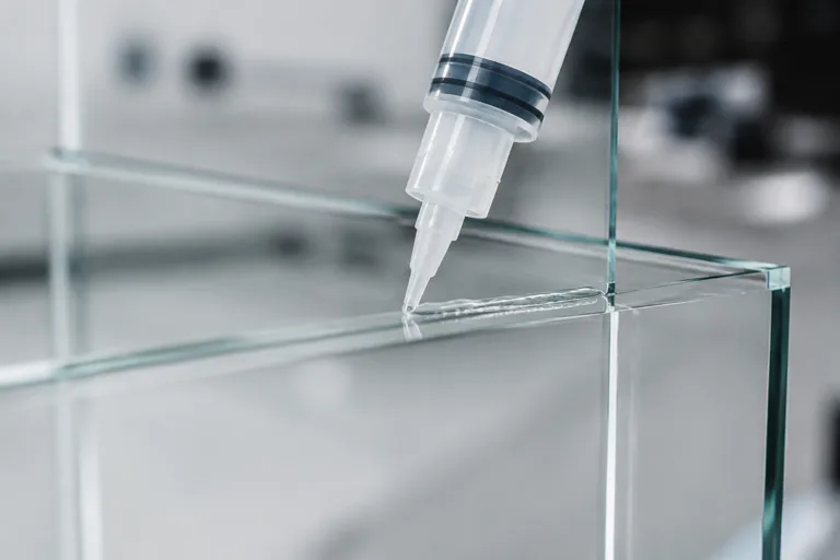 Glass Adhesive 17 A detailed close-up scene showing transparent adhesive application on glass using precision dispensing equipment in a clean industrial setting.