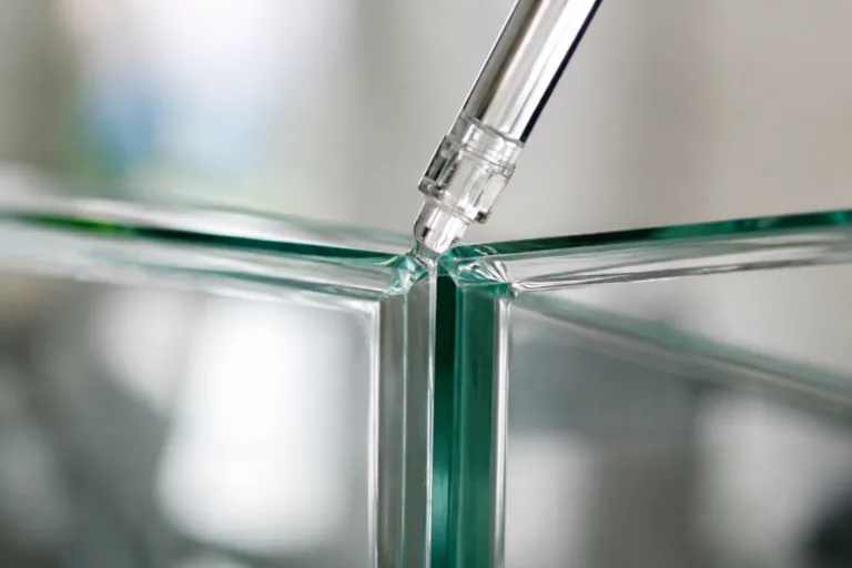 Glass Adhesive 3 A realistic close-up product photography scene showing glass-to-glass bonding with a clean, transparent adhesive seam. The composition emphasizes precision, clarity, and professional industrial assembly details.