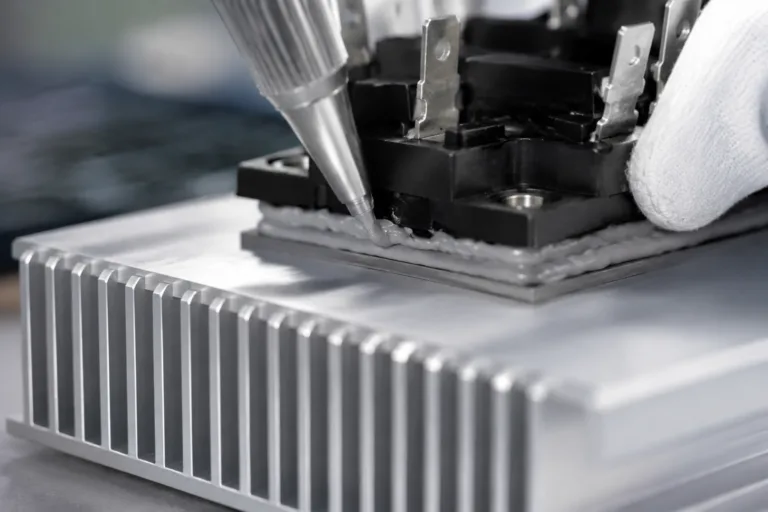 Thermally Conductive Adhesive 6 A realistic close-up industrial assembly scene showing electronic component bonding to an aluminum heat sink with a visible thermal interface layer. Clean, professional product photography with detailed surfaces and no text or watermark.