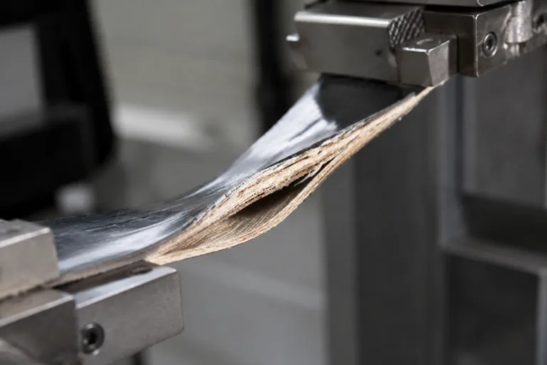 Laminating Adhesive 13 A realistic industrial close-up showing laminated layers under peel or pull testing, highlighting strong adhesive bond performance for manufacturing quality control.