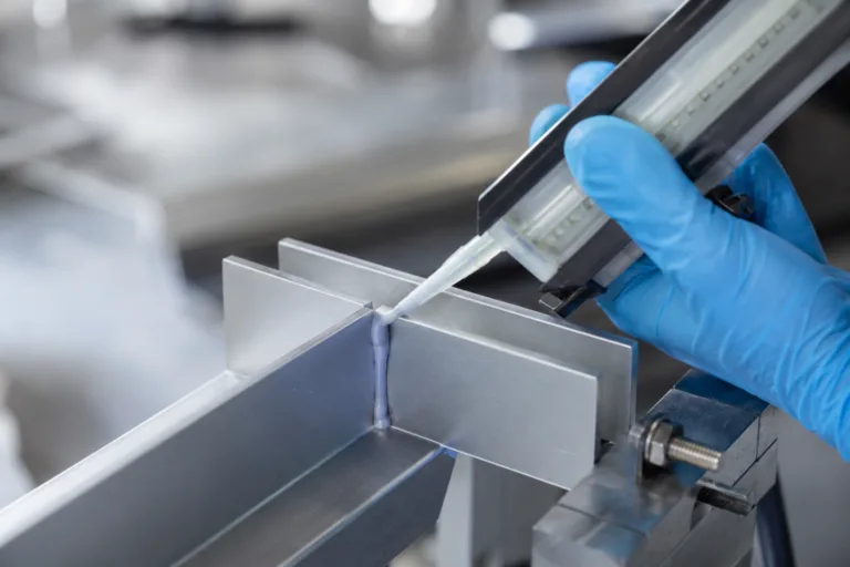Bonding Adhesive 3 A realistic industrial product photography scene showing adhesive joining two metal parts with a visible bonding line in a clean manufacturing environment.
