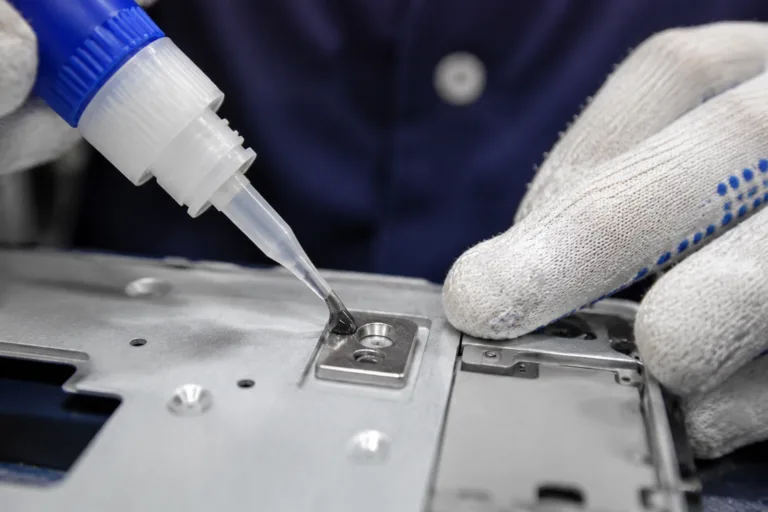 Metal Adhesive 8 A detailed close-up of precision adhesive being used to fix a small bracket, stud, magnet, threaded insert, or metal clip onto a product assembly in a professional manufacturing scene.
