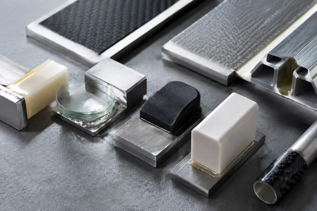 Adhesive Selection & Technical Support 6 Realistic close-up of multi-material bonding test assemblies prepared for industrial adhesive evaluation, featuring diverse material pairings and detailed surface textures.