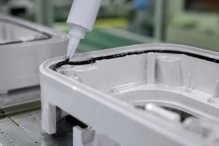 Plastic Adhesive 7 A realistic close-up factory scene showing adhesive bonding and sealing along a plastic housing joint for electronics or sensor products.