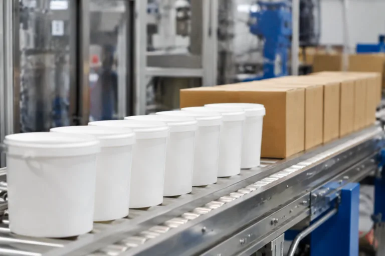 Bulk Adhesive Supply 2 Realistic industrial photography showing consistent adhesive products prepared in repeated batch packaging, with identical cartons and containers lined up neatly in a clean factory setting for reliable recurring supply.