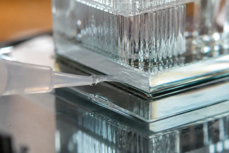 Glass Adhesive 7 A realistic close-up product photography scene showing transparent glass assembly adhesive application with a clean, refined finish, minimal bubbles, and a nearly invisible bond line.