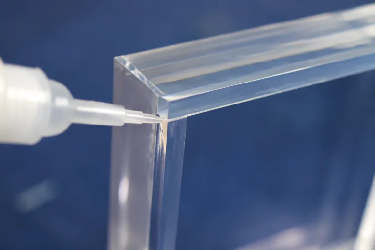 Plastic Adhesive 8 A realistic industrial close-up showing clear adhesive joining transparent plastic or acrylic parts with a clean, nearly invisible bond line, suitable for display or lighting component assembly.