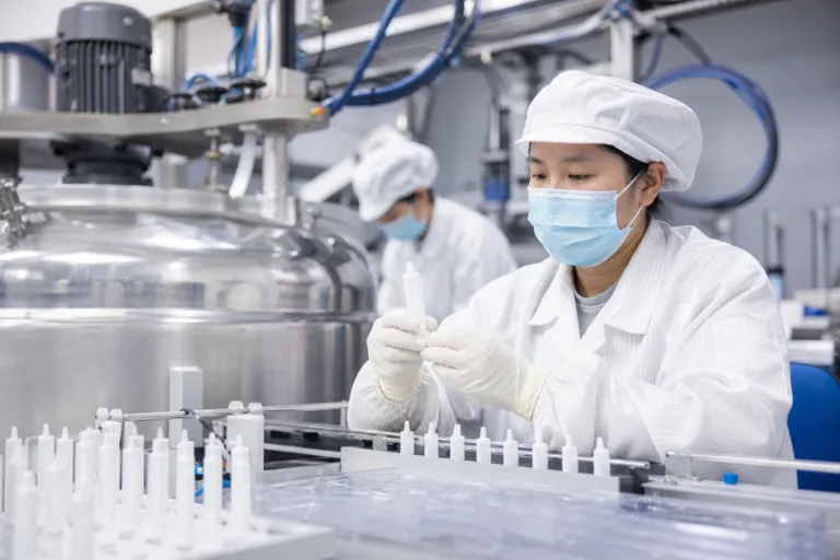 Technicians inspect silicone adhesive cartridges in a controlled industrial production area